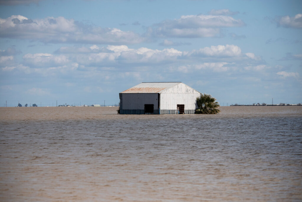 Image of a farm building surrounded on all sides by muddy floodwater