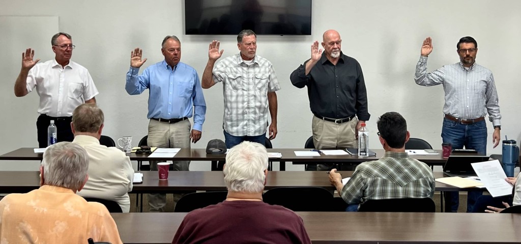 Image of five men raising their hands and being sworn in as board members